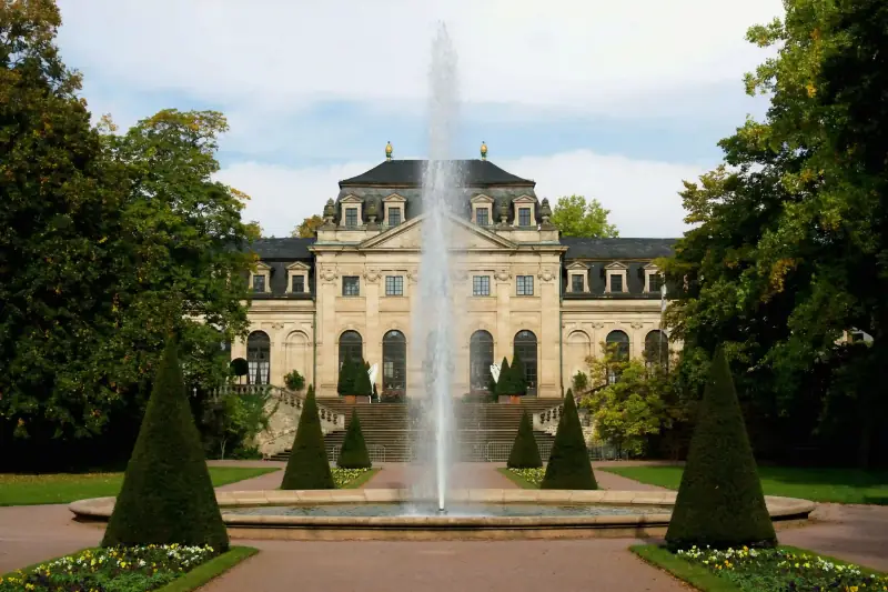 A Regency estate with well-manicured grounds, many trees, and a large fountain in the middle