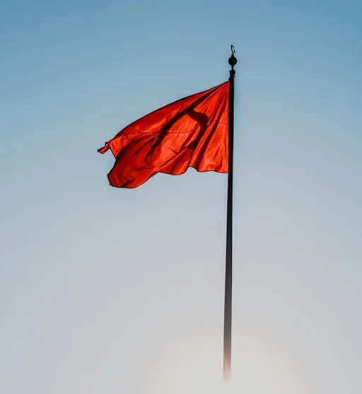 Whimsical woman staring at a literal red flag with a mix of curiosity and dread in a soft pastel world